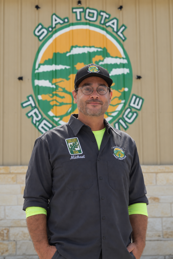 S.A. Total Tree Service team member in uniform in front of tree equipment in Helotes, TX